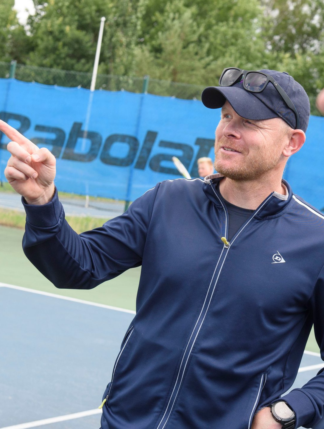 Henrik på utendørs tennisbane, peker og instruerer